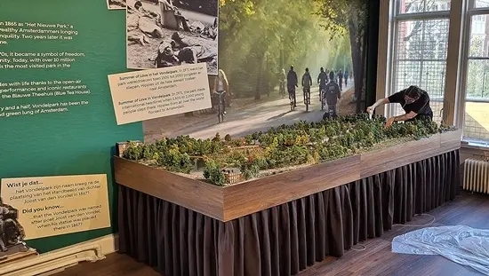 Een modelbouwer werkt de Vondelpark-maquette in het museum af