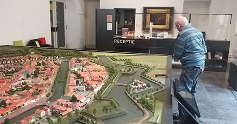 Een collega maakt de maquette van de Vesting Brielle schoon