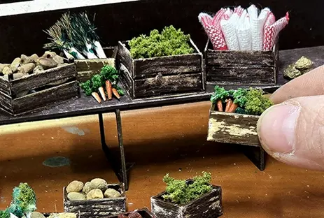 Kistjes met groente, aardappelen en fruit op een miniatuur-marktkraam
